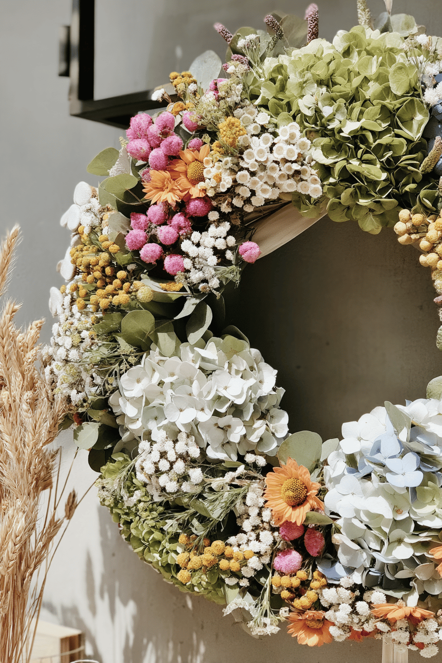 Ein bunter Türkranz mit verschiedenen Blumen, darunter Hortensien und Wiesenblumen.